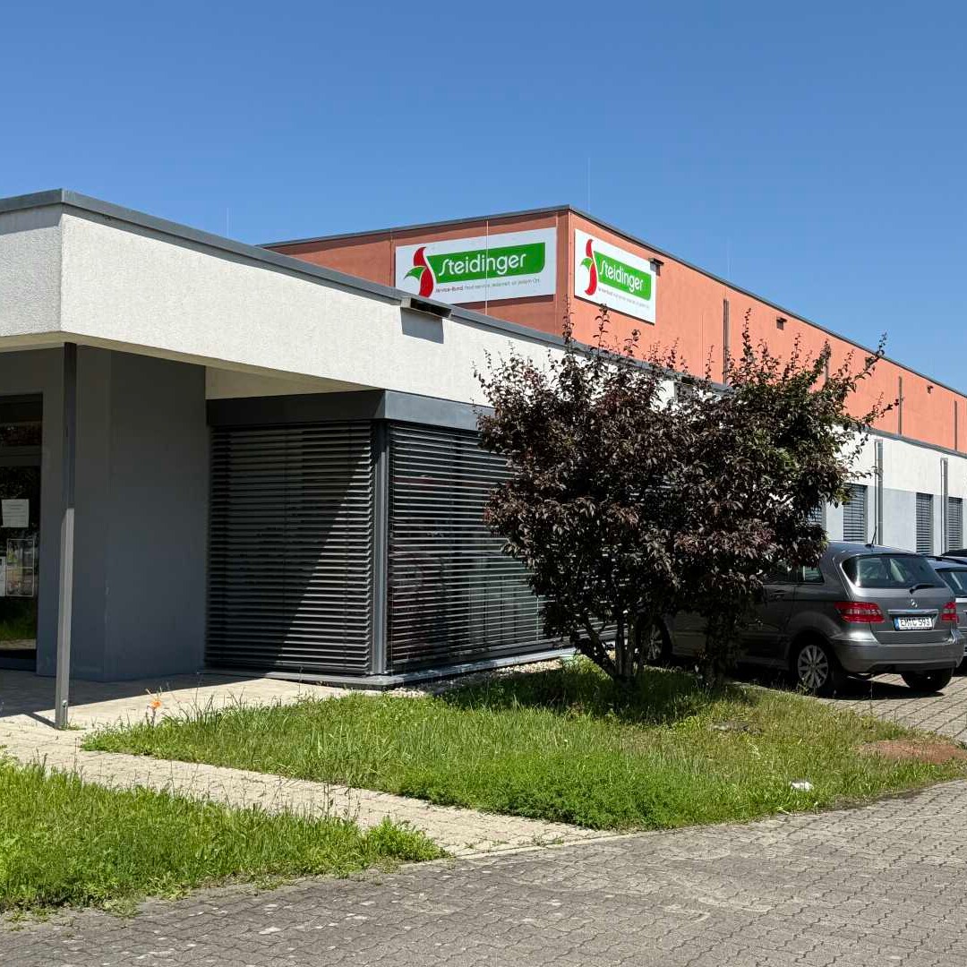 AGBs bei Steidinger Ein Gebäude mit geparkten Autos davor.