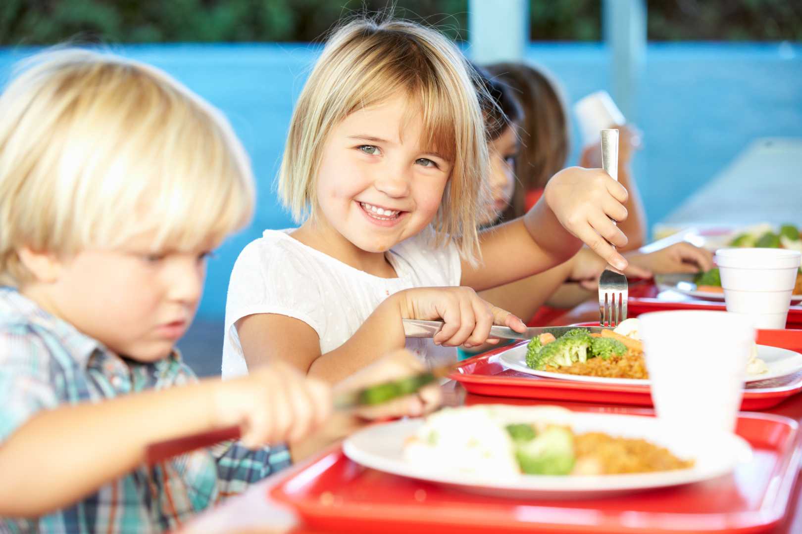 Großhandel für Schulverpflegung, Schulessen, Speiseplanung Eine Gruppe von Kindern isst an einem Tisch.